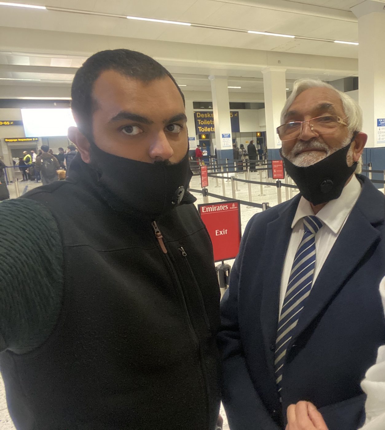 Shaz Ahmed and his father, both in face masks, at Manchester Airport